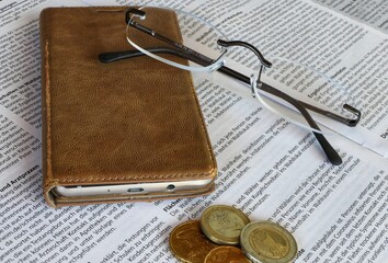 Brille, Smartphone und Eurom&uuml;nzen auf einer Zeitung