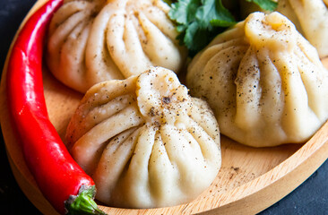 khinkali cooked on a wooden plate black background