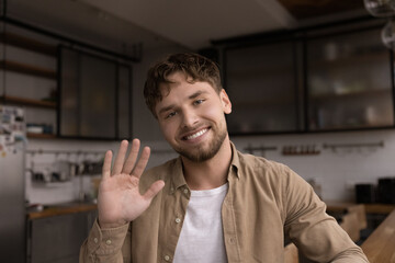 Head shot portrait close up smiling man waving hand at camera, mentor teacher coach greeting viewers, students, leading internet lesson, happy young male chatting with friends online, video call