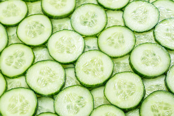 Fresh green slices of cucumber as background.