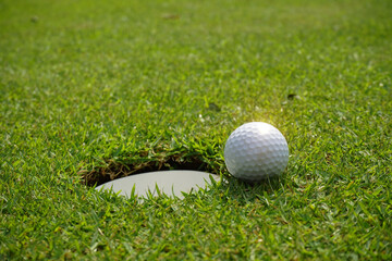 Golf ball and golf hole on green grass.