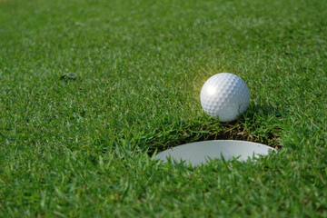 Golf ball and golf hole on green grass.