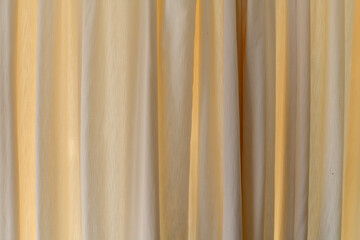 Background of cream curtains backlit by sunlight