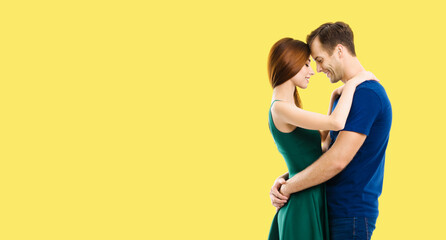 Happy amazed young amorous couple. Profile side portrait of embracing models with closed eyes, in love studio concept, isolated over yellow color background. Man and woman dancing. Copy space.