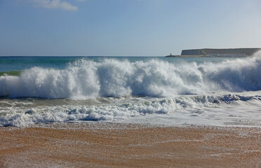 Waves crashing onto a sandy beach in the algarve