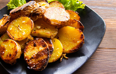 fried potatoes on the grill with herbs on a wooden background