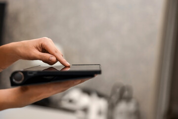 A female hand presses on the screen of a digital tablet close-up, side view. New technology concept, multimedia.