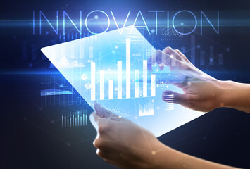 Hand holding futuristic tablet with INNOVATION inscription above, modern business concept