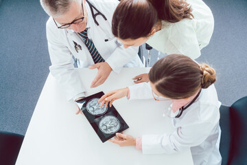 Team of doctors discussing x-ray on a tablet computer