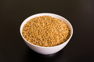 Pile of grits in round white bowl on black table