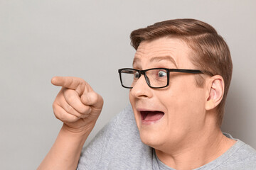 Portrait of happy overjoyed man pointing with finger to the side