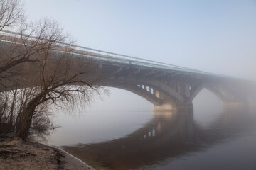 A bridge over a large river.. Fog on the river in early spring