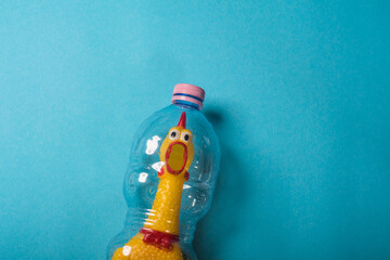 Yellow chicken in a plastic bottle on a blue background.Concept of stop plastic pollution,global warming,recycling plastic,plastic free.