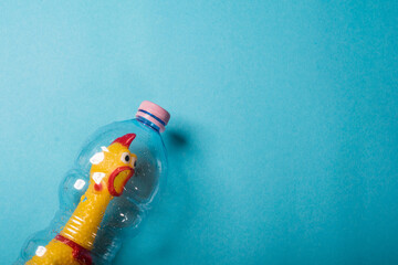 Yellow chicken in a plastic bottle on a blue background.Concept of stop plastic pollution,global warming,recycling plastic,plastic free.