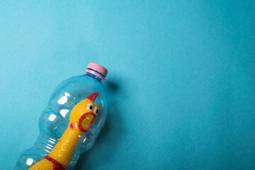 Yellow chicken in a plastic bottle on a blue background.Concept of stop plastic pollution,global warming,recycling plastic,plastic free.