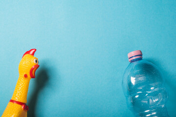 Yellow chicken and plastic bottle on blue backgound.Concept of stop plastic pollution, global warming, recycling plastic, plastic free.