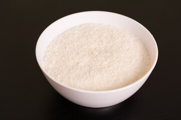 pile of Grated coconut in round white bowl on black table