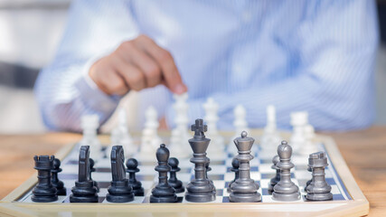 A business man playing a black and white chess game on the board The concept of business strategy for the brain.