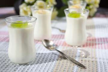 Italian dessert panna cotta in small transparent glasses decorated with grapes and banana on a checkered tablecloth