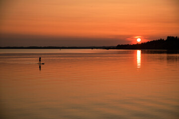 Ein Standuppaddler auf einem See im Sonnenuntergang