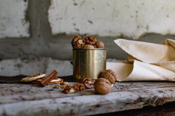 Walnuts in a tin of yellow metal next to the shell and the nuts on the inside. Decorated with dried oranges and a cinnamon stick. Composition of products and food on a wooden Board