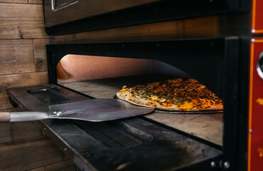 A pizza in a oven burning. Pizza is taken straight from the oven