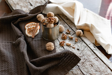 Walnuts in a tin of yellow metal next to the shell and the nuts on the inside. Decorated with dried oranges and a cinnamon stick. Composition of products and food on a wooden Board