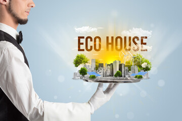 Waiter serving eco city with ECO HOUSE inscription, renewabke energy concept