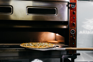 A pizza in a oven burning. Pizza is taken straight from the oven