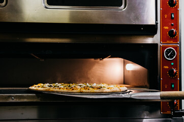 A pizza in a oven burning. Pizza is taken straight from the oven