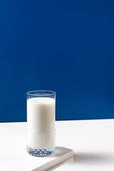 Vaso de leche fresca en mesa blanca sobre fondo azul