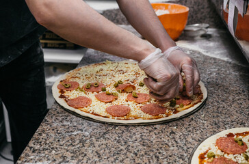 Pizzaiola straightens pizza dough in pizzeria