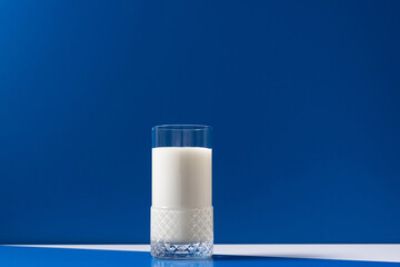 Vaso de leche fresca en mesa blanca sobre fondo azul