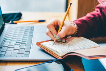 Woman writing at notebook and working on laptop at caffe.