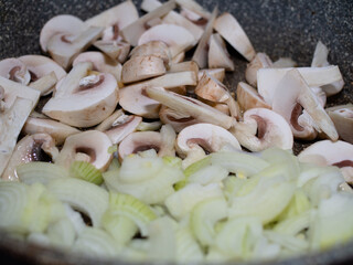 cut raw mushrooms in a frying pan with . cooking dinner.