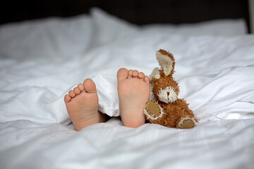 Cute child, lying in bed, playing with little stuff toy