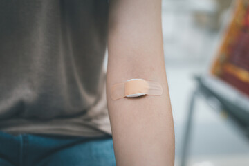 Plaster and cotton on woman arm after blood testing or blood donation.