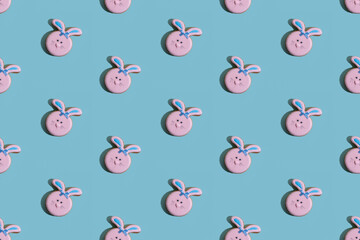 Food background. Seamless pattern. Bunny bakery art. Festive decor. Pretty rabbit gingerbread cookies with pink icing smiling faces isolated on blue textured.