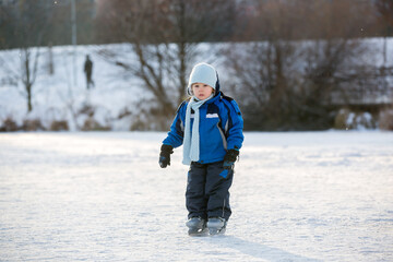 Fototapeta na wymiar Happy children, skating on a frozen lake in the park