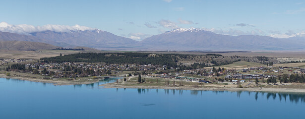 Lake Tekapo with nearby snow covered mountain peaks on a sunny day in the South Island of New Zealand.