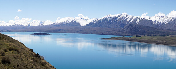 Lake Tekapo with nearby snow covered mountain peaks on a sunny day in the South Island of New Zealand.