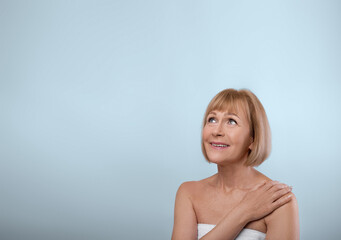 Fototapeta premium Graceful aging concept. Attractive senior woman with silky soft skin looking at empty space on blue studio background