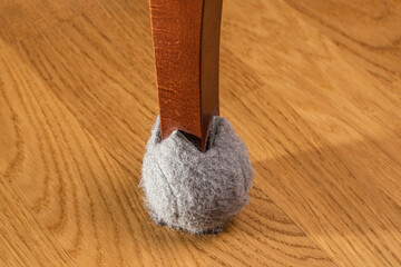 Close up view of brown chair leg with floor protection. Sweden.