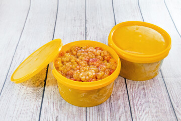 Frozen cloudberries in yellow plastic containers