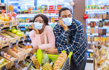 Black family in face masks buying food, tired of shopping for groceries at supermarket during covid-19 outbreak