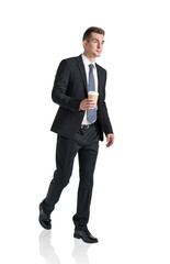 Handsome businessman in formal suit walking with cup of coffee in hands. Isolated on white background