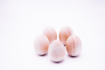 Five hand-made unpainted wooden eggs on a white background