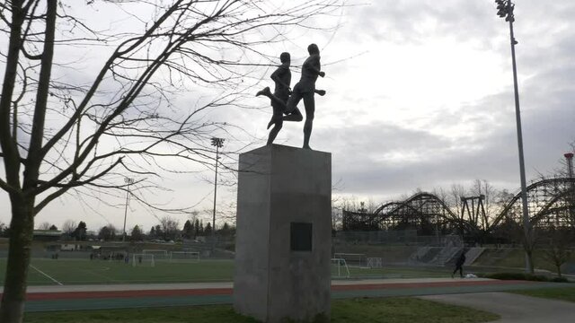 Hyperlapse Shot Of John Landy And Roger Bannister Miracle Mile Bronze Statue In Vancouver. Soccer Field And Empire Stadium. Track Shot.