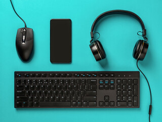 Headphones, smartphone, pc mouse and desktop computer keyboard on a turquoise background. Modern devices and gadgets. Distance learning, online business, working and shopping concepts.