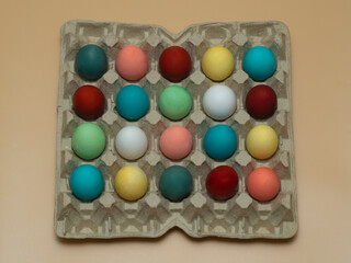 Multicolored colored, boiled chicken eggs in factory, store cardboard packaging, backing. The concept of buying or selling decorated products and food for Easter. Top view.